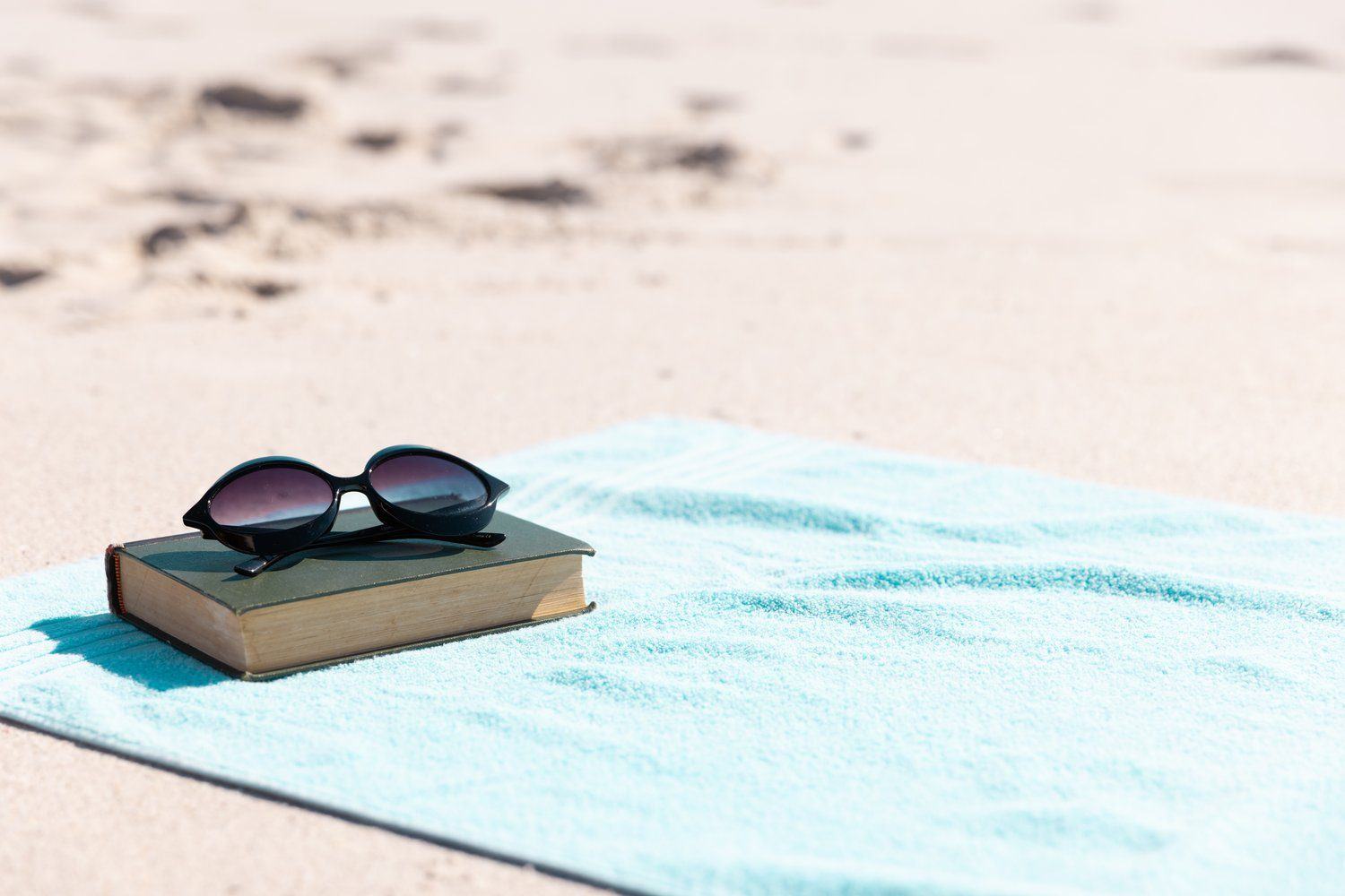 Książka w miękkiej okładce na ręczniku plażowym
